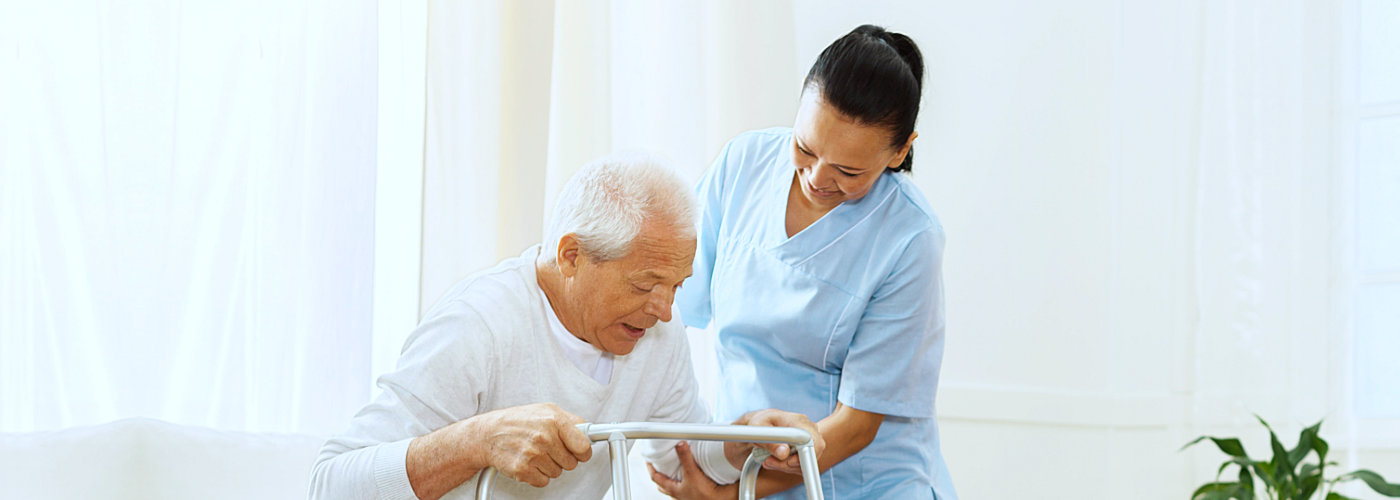 caregiver assisting senior man to stand in an adult home